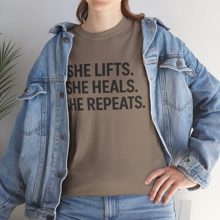 She Lifts. She Heals. She Repeats.  Unisex Heavy Cotton Tee