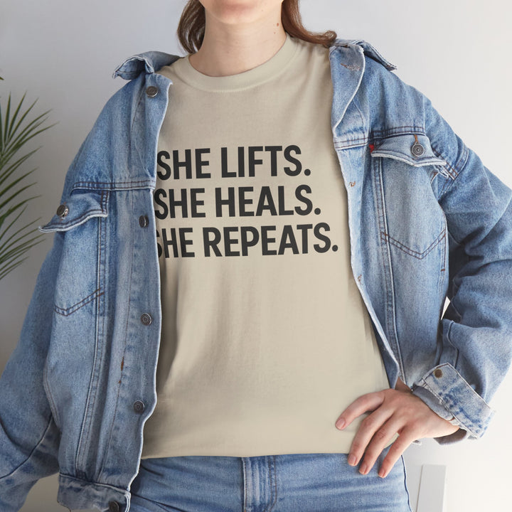 She Lifts. She Heals. She Repeats.  Unisex Heavy Cotton Tee