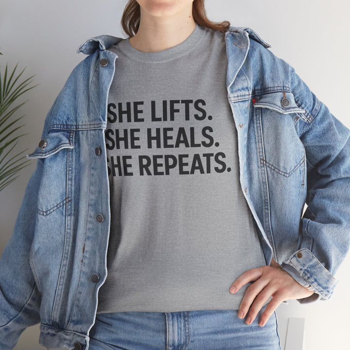 She Lifts. She Heals. She Repeats.  Unisex Heavy Cotton Tee
